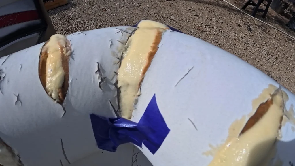 Tan FlexFoam-iT! X foam bulging out of three splits in a white pontoon seat, with blue tape in the middle.