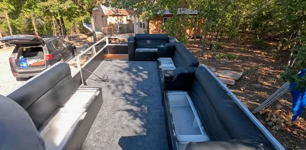 Wide view of a pontoon deck with black seats and gray carpet.