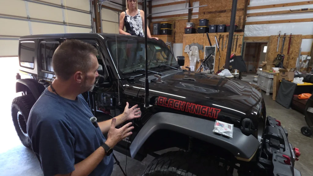 Ryan explaining the Topsy fender antenna mount next to a black Jeep Wrangler